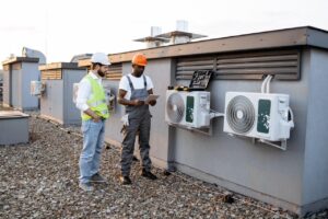 HVAC workers with tablet fixing rtu air conditioner on plant roof